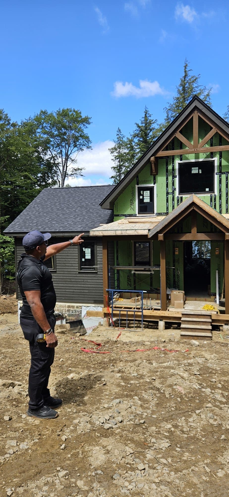 Walking a new build in Muskoka: one wing freshly painted deep green, stained timber porch posts, the rest of the shell still wrapped